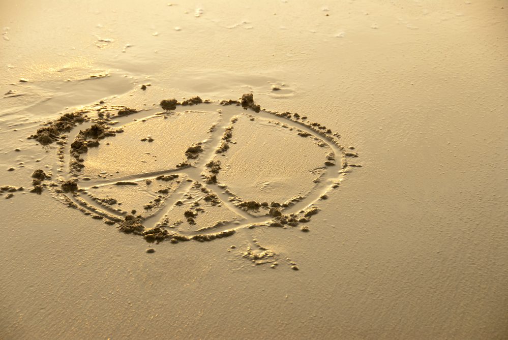 A peace sign drawn in the sand on the beach.