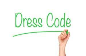 A person writing dress code on a white board