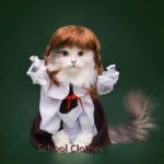 A cat dressed in school clothes and holding its mouth open.