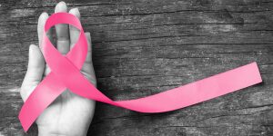A hand holding onto a pink ribbon