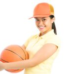 A girl holding an orange basketball in her hands.