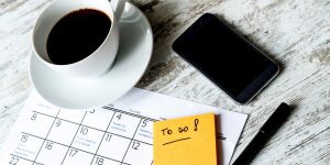 A cup of coffee, phone and calendar on the table.
