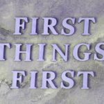 A purple sign that says first things first.