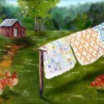 Quilts hanging outdoors near a red barn
