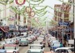 A busy street with cars and decorations hanging from the ceiling.