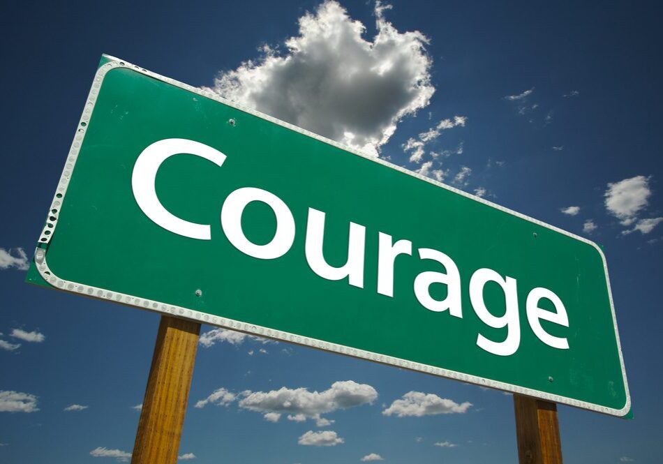 A green street sign with the word " courage " on it.
