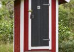 A red and white outhouse with steps leading to it.