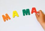 A child holding letters that spell out mama.