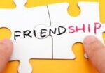 A person holding two pieces of puzzle that have the word " friendship " written on them.