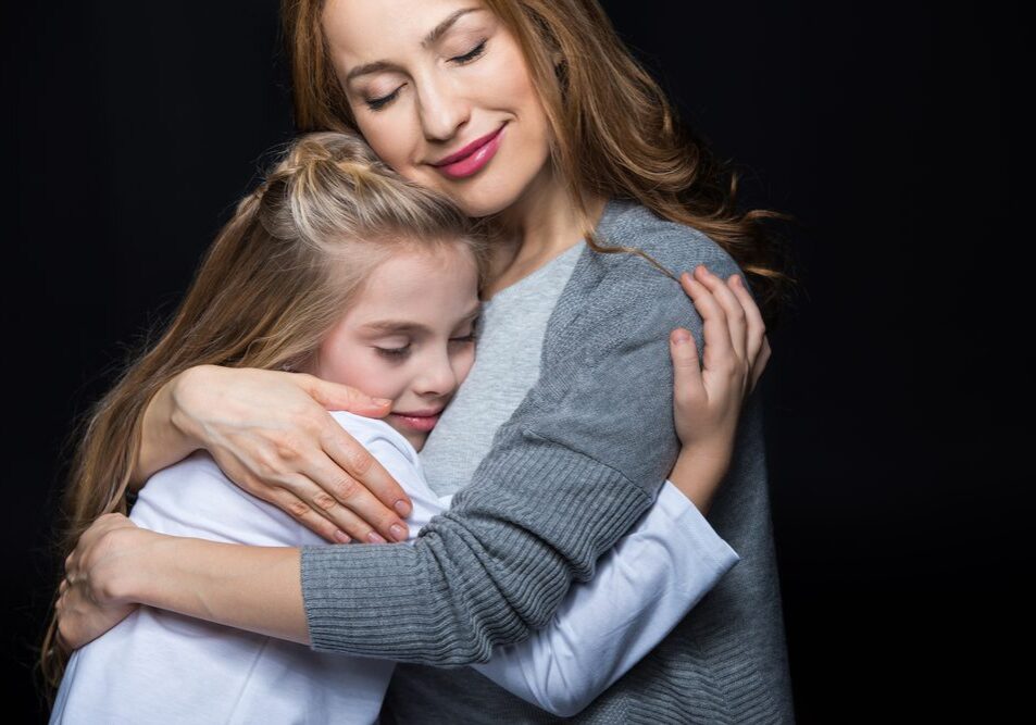 A woman and girl hugging each other.