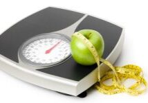 A scale with an apple and measuring tape on it.