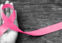 A hand holding onto a pink ribbon