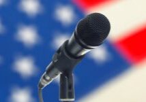 A microphone is shown in front of an american flag.