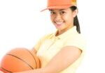 A girl holding an orange basketball in her hands.