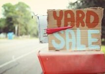 A yard sale sign sitting on top of a red wagon.